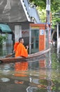 A young buddhist monk keeps smiling as he is rowing his boat in a flooded street of Bangkok, Thailand on the 11th of November 2011