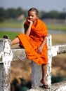 Young Buddhist monk sitting on a bridge
