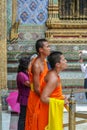 Young Buddhist monks as tourists walking around territory of Grand Palace. Ancient architecture of Asia.