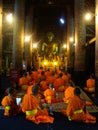Young Buddhist monks pray at large gold Buddha statue, Laos