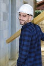 young builder carrying wood on shoulder Royalty Free Stock Photo
