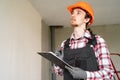 Young builder or contractor in protective hard hat holding clipboard with papers document. Male worker at construction site Royalty Free Stock Photo