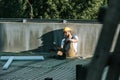 young builder in hardhat and protective googles using smartphone and resting at construction