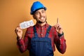 Young builder man wearing safety helmet offering help and support over yellow background surprised with an idea or question Royalty Free Stock Photo