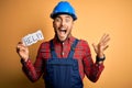 Young builder man wearing safety helmet offering help and support over yellow background very happy and excited, winner expression Royalty Free Stock Photo