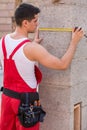 Young builder measuring wall