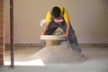 Young builder sieving sand at a construction site.