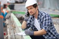 young builder talking mobile phone at construction site