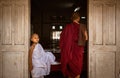 Young Burmese monk in white robe at Maha Gandaryon monastery waits at dining hall door