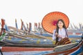 A young Burmese woman holding a red umbrella sitting on a gondola. U-bein bridge, Mandalay, Myanmar Royalty Free Stock Photo