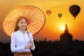 Young Burmese woman with a red umbrella. Young girl and Sunrise many hot air balloon with stupas in Bagan, Myanmar. space for text Royalty Free Stock Photo