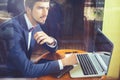 Young businesman working at cafe, using laptop