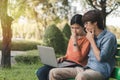 Young business asian man and woman working with laptop and thinking about online business on bench in the park outdoors on Royalty Free Stock Photo