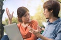 Young business asian man and woman working with them laptop and talking serious  on a bench in the park outdoors on vacation time Royalty Free Stock Photo