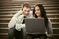 Young business couple with laptop on the steps Royalty Free Stock Photo