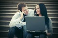 Young business couple with laptop on the steps Royalty Free Stock Photo