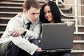 Young business couple with laptop on the steps Royalty Free Stock Photo