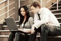 Young business couple with laptop on the steps Royalty Free Stock Photo