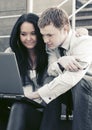 Young business couple using laptop on the steps Royalty Free Stock Photo