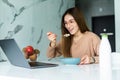 Young business entrepreneur woman working at home while having breakfast using laptop computer in the kitchen. Working online Royalty Free Stock Photo