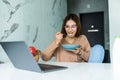 Young business entrepreneur woman working at home while having breakfast using laptop computer in the kitchen. Working online Royalty Free Stock Photo
