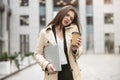 Young business lady holding laptop under arm having unpleasant smartphone conversation walking down the street near office center Royalty Free Stock Photo