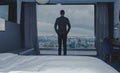 Young business man on the background of the panoramic windows with the view on the city from the hotel room Royalty Free Stock Photo