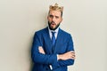 Young business man with beard wearing king crown in shock face, looking skeptical and sarcastic, surprised with open mouth Royalty Free Stock Photo