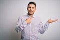 Young business man with blue eyes standing over isolated background amazed and smiling to the camera while presenting with hand Royalty Free Stock Photo