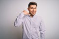 Young business man with blue eyes standing over isolated background smiling doing phone gesture with hand and fingers like talking Royalty Free Stock Photo