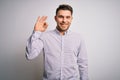 Young business man with blue eyes standing over isolated background smiling positive doing ok sign with hand and fingers Royalty Free Stock Photo