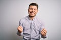 Young business man with blue eyes standing over isolated background very happy and excited doing winner gesture with arms raised, Royalty Free Stock Photo