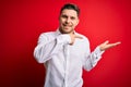 Young business man with blue eyes wearing elegant shirt standing over red isolated background amazed and smiling to the camera Royalty Free Stock Photo