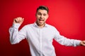 Young business man with blue eyes wearing elegant shirt standing over red isolated background Dancing happy and cheerful, smiling Royalty Free Stock Photo
