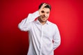 Young business man with blue eyes wearing elegant shirt standing over red isolated background doing ok gesture with hand smiling, Royalty Free Stock Photo