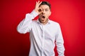 Young business man with blue eyes wearing elegant shirt standing over red isolated background doing ok gesture shocked with Royalty Free Stock Photo