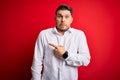 Young business man with blue eyes wearing elegant shirt standing over red isolated background Pointing aside worried and nervous Royalty Free Stock Photo