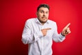 Young business man with blue eyes wearing elegant shirt standing over red isolated background Pointing aside worried and nervous Royalty Free Stock Photo