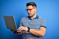 Young business man with blue eyes wearing glasses working using computer laptop with a confident expression on smart face thinking Royalty Free Stock Photo