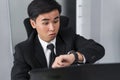 Business man checking time on watch while using laptop Royalty Free Stock Photo