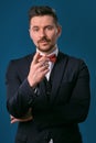 Young business man in classic black suit, white shirt and red bow-tie. Posing against a blue studio background. Mock up Royalty Free Stock Photo