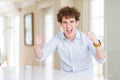 Young business man with curly read head angry and mad raising fists frustrated and furious while shouting with anger