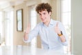 Young business man with curly read head approving doing positive gesture with hand, thumbs up smiling and happy for success Royalty Free Stock Photo