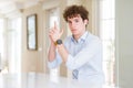 Young business man with curly read head Holding symbolic gun with hand gesture, playing killing shooting weapons, angry face