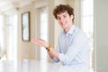 Young business man with curly read head pointing aside with hands open palms showing copy space, presenting advertisement smiling Royalty Free Stock Photo