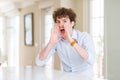Young business man with curly read head Shouting angry out loud with hands over mouth Royalty Free Stock Photo