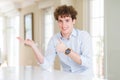 Young business man with curly read head Showing palm hand and doing ok gesture with thumbs up, smiling happy and cheerful Royalty Free Stock Photo