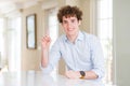 Young business man with curly read head showing and pointing up with finger number one while smiling confident and happy Royalty Free Stock Photo