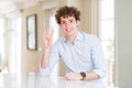 Young business man with curly read head showing and pointing up with fingers number four while smiling confident and happy Royalty Free Stock Photo