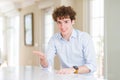 Young business man with curly read head smiling cheerful offering palm hand giving assistance and acceptance Royalty Free Stock Photo